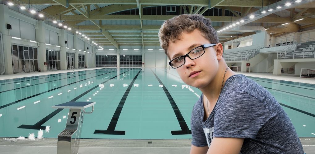 Un jeune garçon devant une piscine où il travaille.
