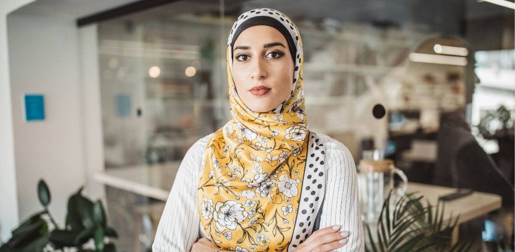 Une femme portant le hijab pose dignement en regardant la caméra dans son milieu de travail.