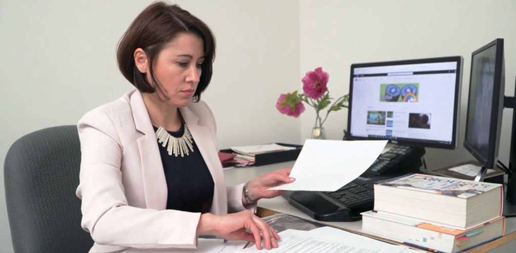 Une employée dans un bureau face à son ordinateur traitant un dossier. 