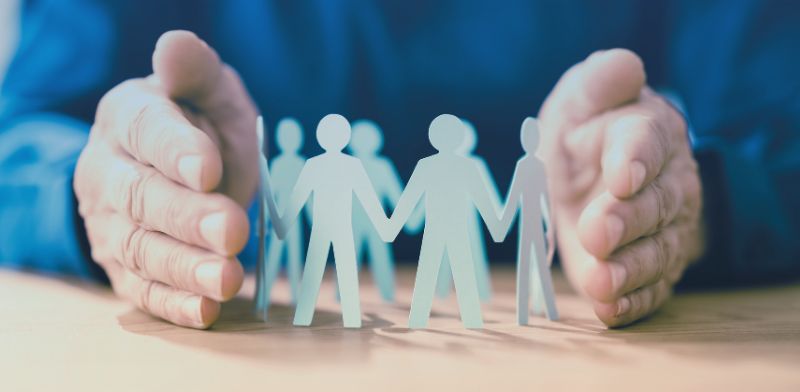 Des mains entourant des silhouettes en papier.