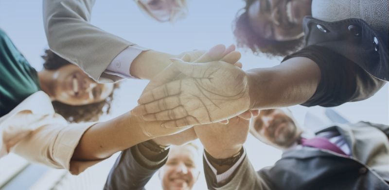 Des personnes d'origines diverses vues en contre-plongée qui se tiennent la main. 