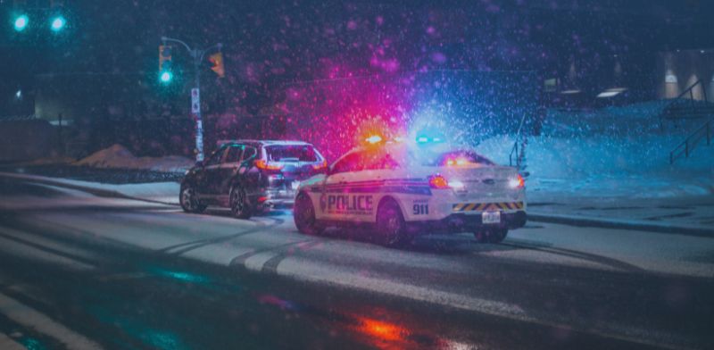 Voiture de police avec ses gyrophares allumés derrière un véhicule. 