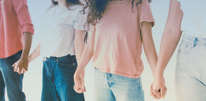Corps de quatre jeunes femmes habillées de façon décontractée se tenant la main.